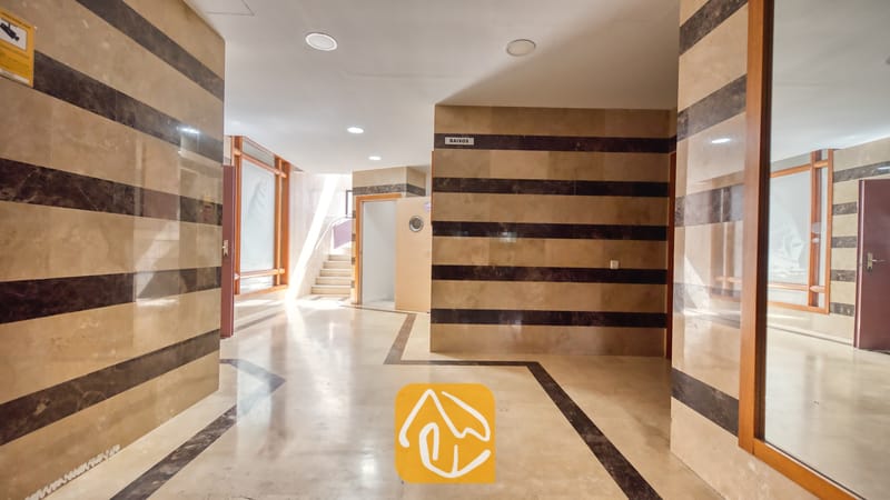 Vakantievilla's Costa Brava Spanje - Apartment Dali - Binnenhal voorzien van beige en donkerbruin gestreepte tegelmuren, lichte marmeren vloeren, inbouwspots in het plafond en een deuropening met de aanduiding BAIXOS in Appartement Dali.
