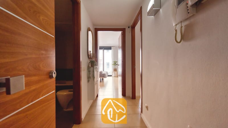 Vakantievilla's Costa Brava Spanje - Apartment Dali - Binnenhal met lichte tegelvloer, witte muren en houten deurposten die toegang bieden tot de verschillende kamers van Appartement Dali.