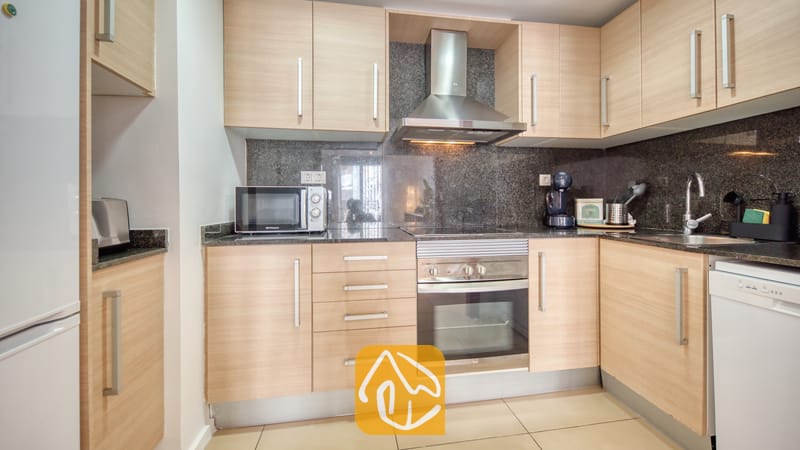 Vakantievilla's Costa Brava Spanje - Apartment Dali - Keuken van Appartement Dali, voorzien van lichte houten kasten, donkere granieten aanrechtbladen en roestvrijstalen apparatuur, waaronder een oven en afzuigkap.
