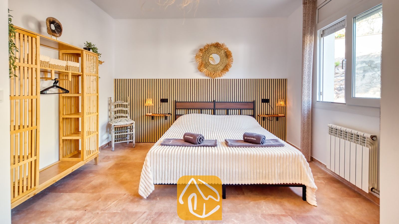 Vakantievilla's Costa Brava Spanje - Villa Ibiza - Slaapkamer met een tweepersoonsbed, voorzien van opgerolde handdoeken, een houten lamellen hoofdborden, een bamboe kledingkast en een tegelvloer.