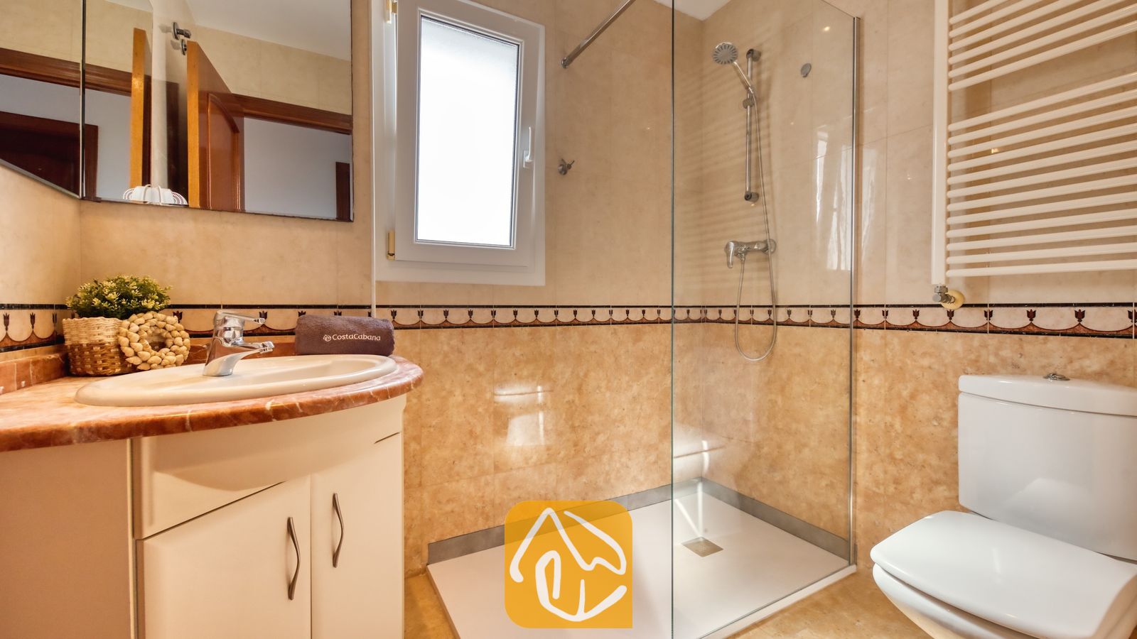 Vakantievilla's Costa Brava Spanje - Villa Ibiza - Moderne badkamer met betegelde wanden in een beige tint, een glazen inloopdouche, een wit badmeubel met een ronde wastafel en een wit toilet.