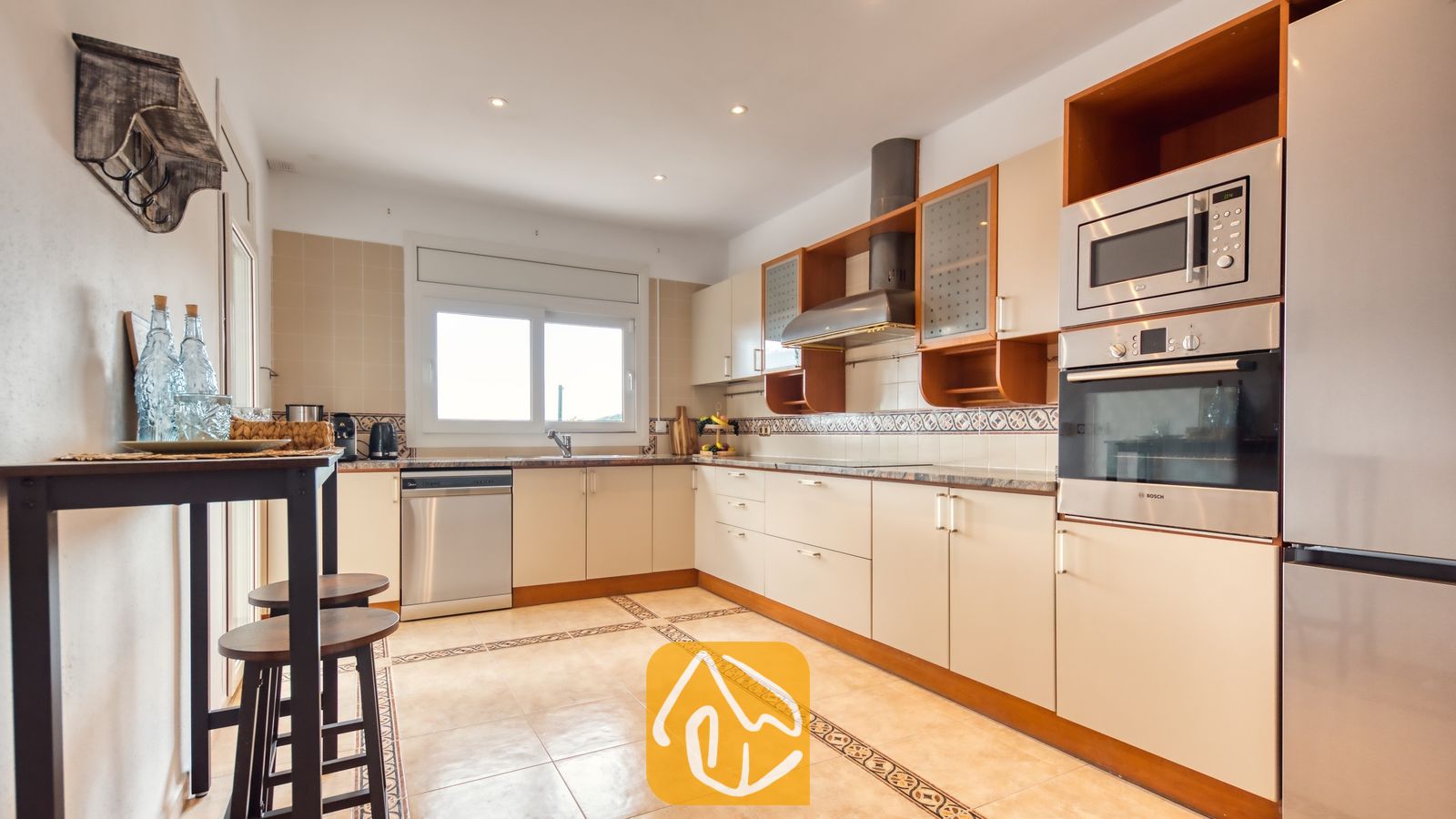 Vakantievilla's Costa Brava Spanje - Villa Ibiza - Keuken met lichtbeige kasten, inbouwapparatuur van roestvrij staal en tegelvloeren in Villa Ibiza.