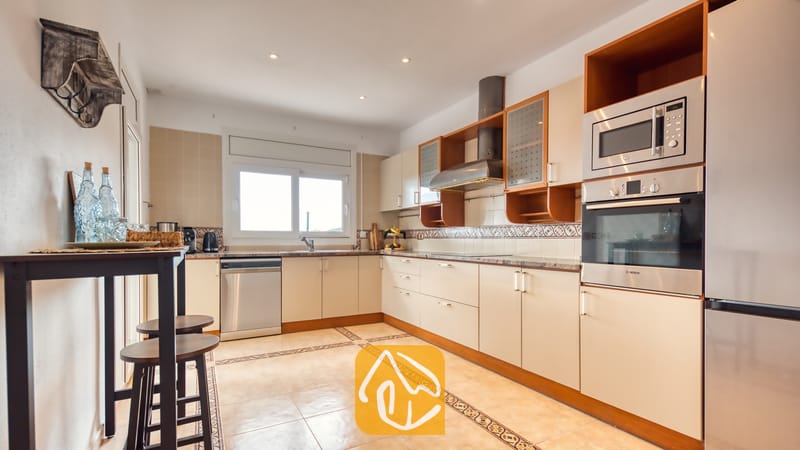Villas de vacances Costa Brava Espagne - Villa Ibiza - Cuisine équipée de placards beige clair, d'appareils électroménagers en acier inoxydable et de sols carrelés à la Villa Ibiza.