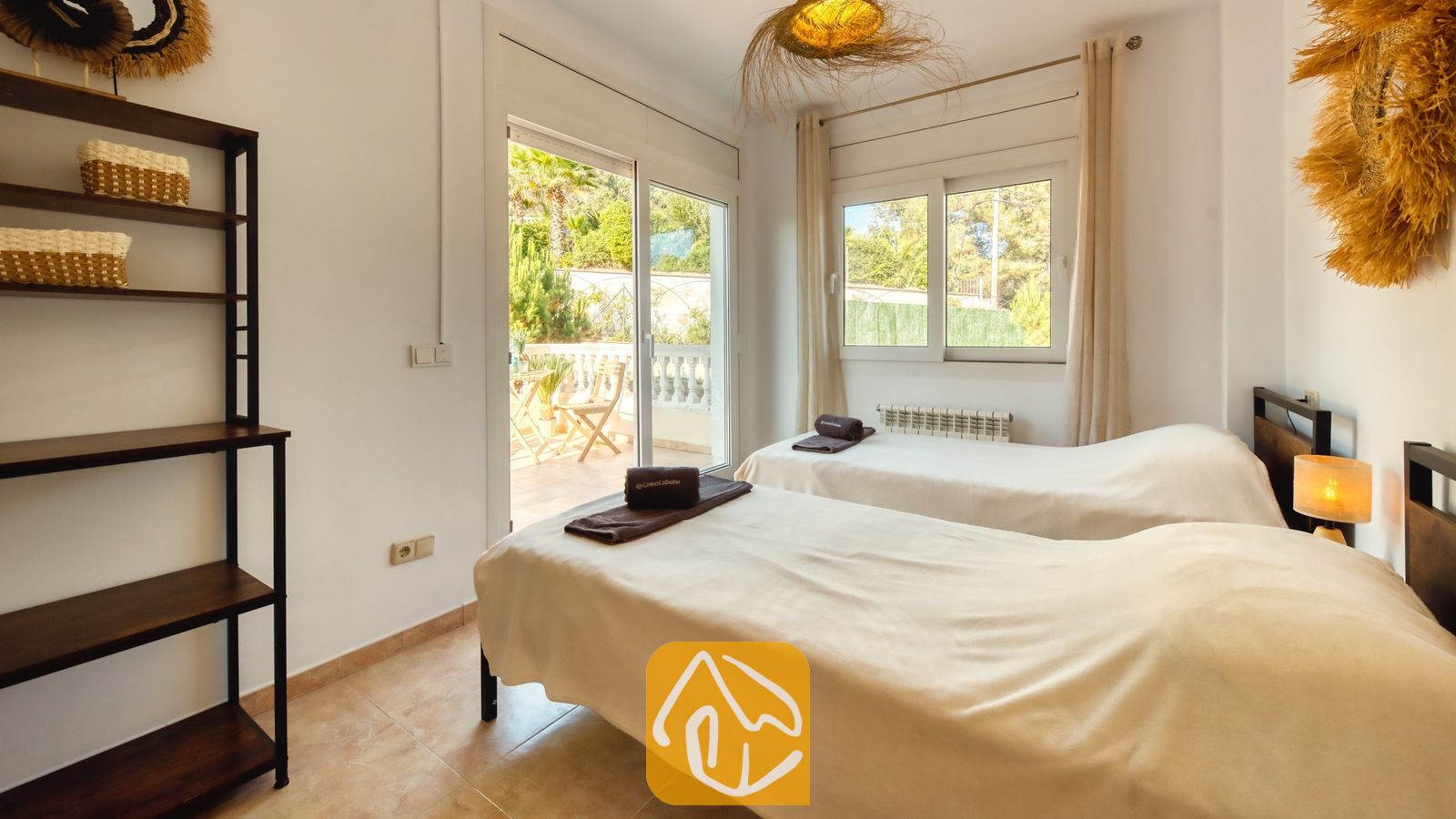 Vakantievilla's Costa Brava Spanje - Villa Ibiza - Slaapkamer met twee eenpersoonsbedden, neutraal beddengoed, een donkerhouten kast en een schuifpui die uitkomt op een zonnig terras.