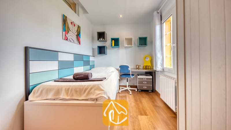 Villas de vacances Costa Brava Espagne - Villa Soleia - Chambre simple avec une tête de lit à motifs bleu et blanc, parquet et coin bureau avec chaise bleue