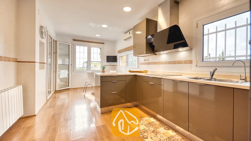 Villas de vacances Costa Brava Espagne - Villa Soleia - Cuisine moderne dotée de meubles brun brillant, d'une hotte aspirante en acier inoxydable, de parquets en bois et d'une fenêtre munie de barreaux de sécurité
