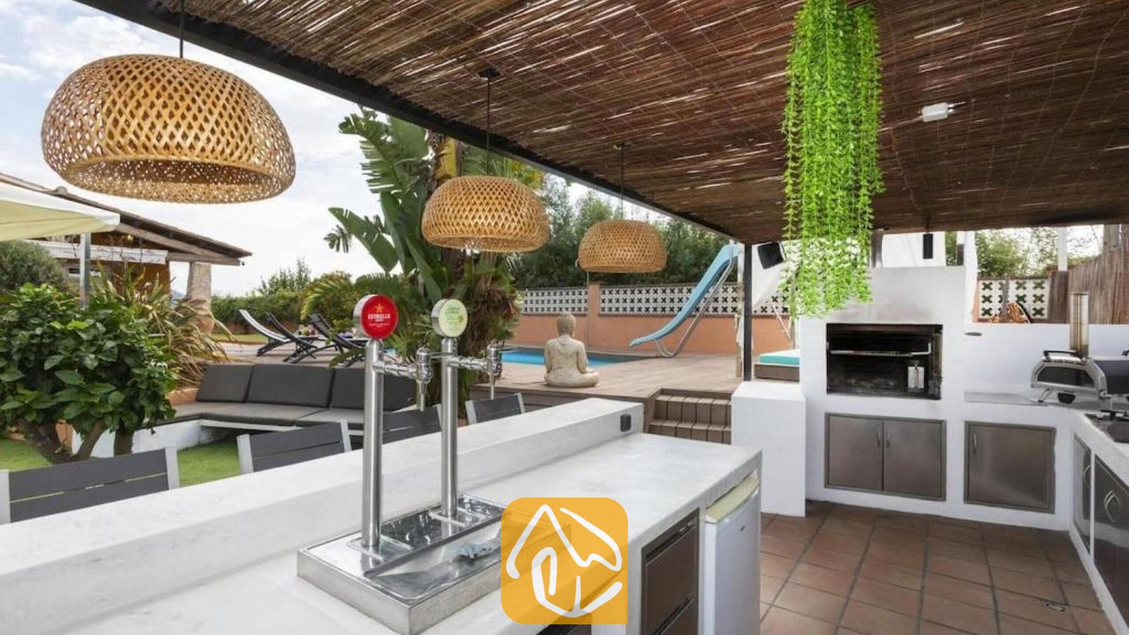 Vakantievilla's Costa Brava Spanje - Villa Soleia - Overdekte buitenbar met biertap bij Villa Soleia, voorzien van een ingebouwde barbecue, rieten hanglampen en uitzicht op het zwembad op de achtergrond.