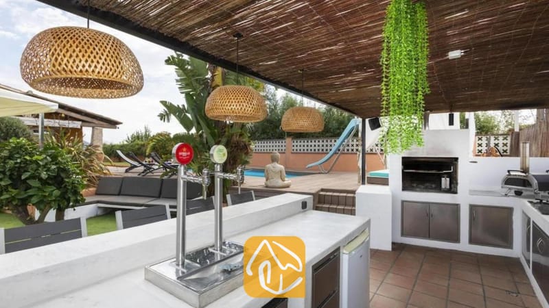 Vakantievilla's Costa Brava Spanje - Villa Soleia - Overdekte buitenbar met biertap bij Villa Soleia, voorzien van een ingebouwde barbecue, rieten hanglampen en uitzicht op het zwembad op de achtergrond.