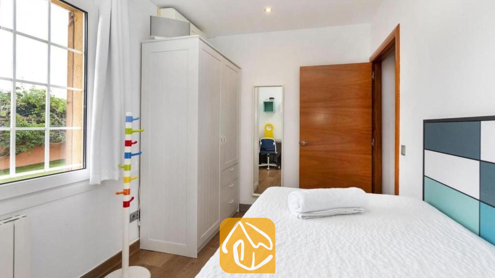 Vakantievilla's Costa Brava Spanje - Villa Soleia - Slaapkamer met een witte kledingkast, een houten deur en een bed met blauw-witte hoofdbordpanelen.