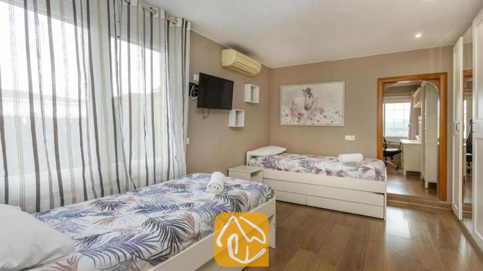 Vakantievilla's Costa Brava Spanje - Villa Soleia - Slaapkamer met twee eenpersoonsbedden voorzien van beddengoed met patroon, grote gestreepte gordijnen en een wandgemonteerde flatscreen-tv in Villa Soleia