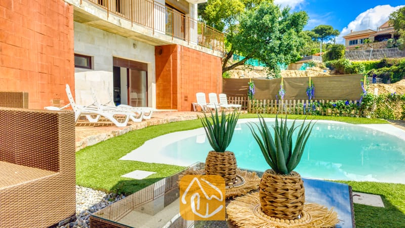 Vakantievilla's Costa Brava Spanje - Villa Sunny Beach - Privézwembad met een gebogen, blauw waterbassin, omringd door kunstgras, witte ligstoelen en terracotta buitenmuren bij Villa Sunny Beach.
