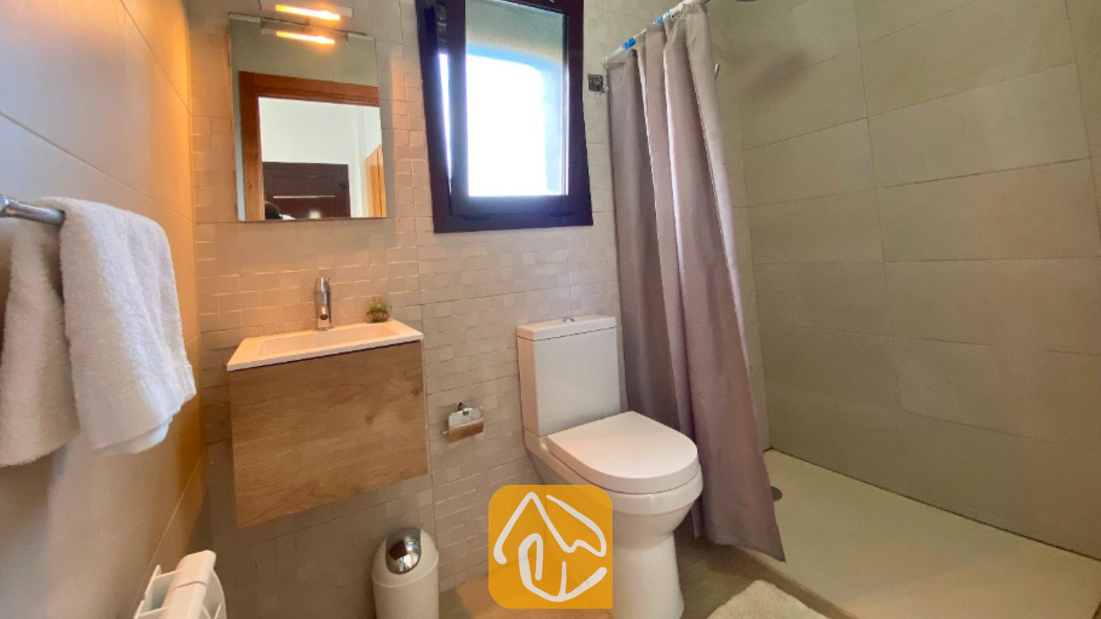 Vakantievilla's Costa Brava Spanje - Villa Sunny Beach - Moderne badkamer met een houten badkamermeubel, een wit toilet en een inloopdouche met een grijs gordijn.