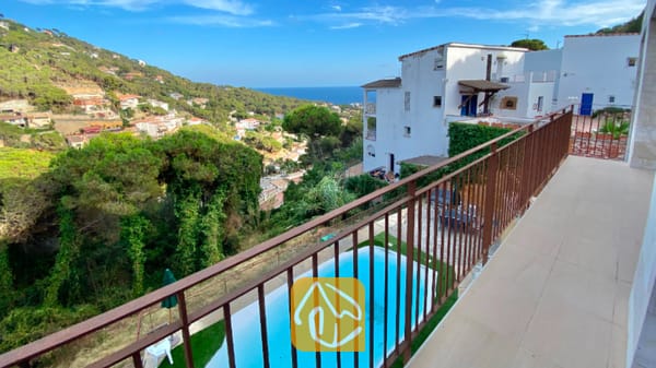 Vakantievilla's Costa Brava Spanje - Villa Sunny Beach - Uitzicht vanaf het balkon van Villa Sunny Beach op een zwembad, beboste heuvels en de zee in Spanje.