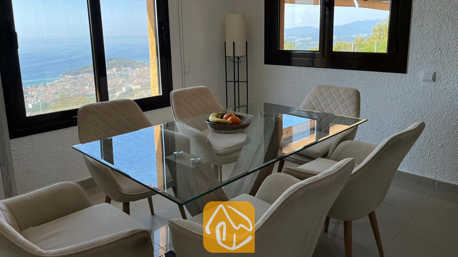 Vakantievilla's Costa Brava Spanje - Villa VistaMar - Eethoek in Villa VistaMar met een glazen tafel, zes gestoffeerde stoelen en grote ramen met uitzicht op de kust.