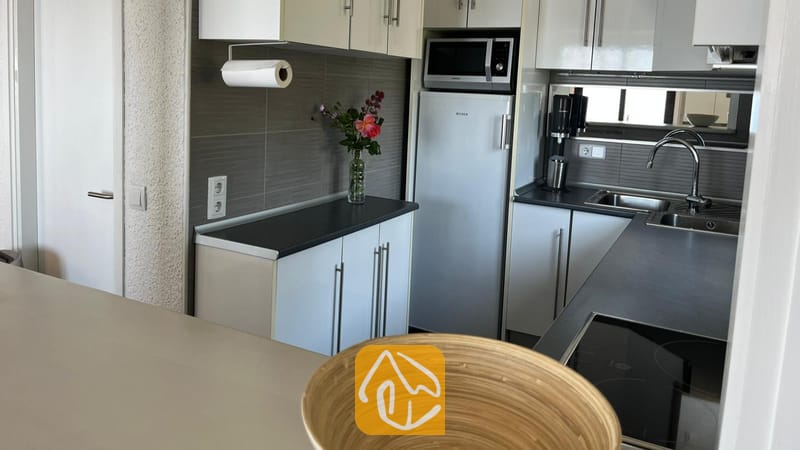 Vakantievilla's Costa Brava Spanje - Villa VistaMar - Compacte keuken met witte kasten, donkere aanrechtbladen, een roestvrijstalen koelkast en een inbouwmagnetron.