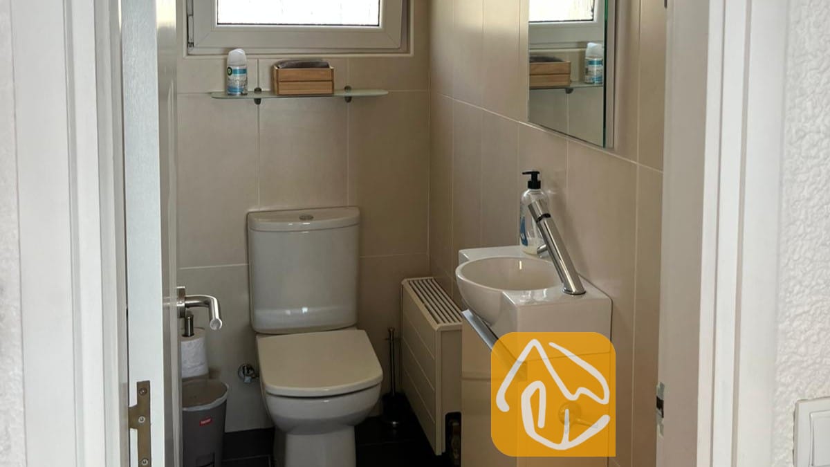 Vakantievilla's Costa Brava Spanje - Villa VistaMar - Kleine, betegelde badkamer met een wit toilet, een compacte wastafel met een moderne kraan en een wandspiegel.