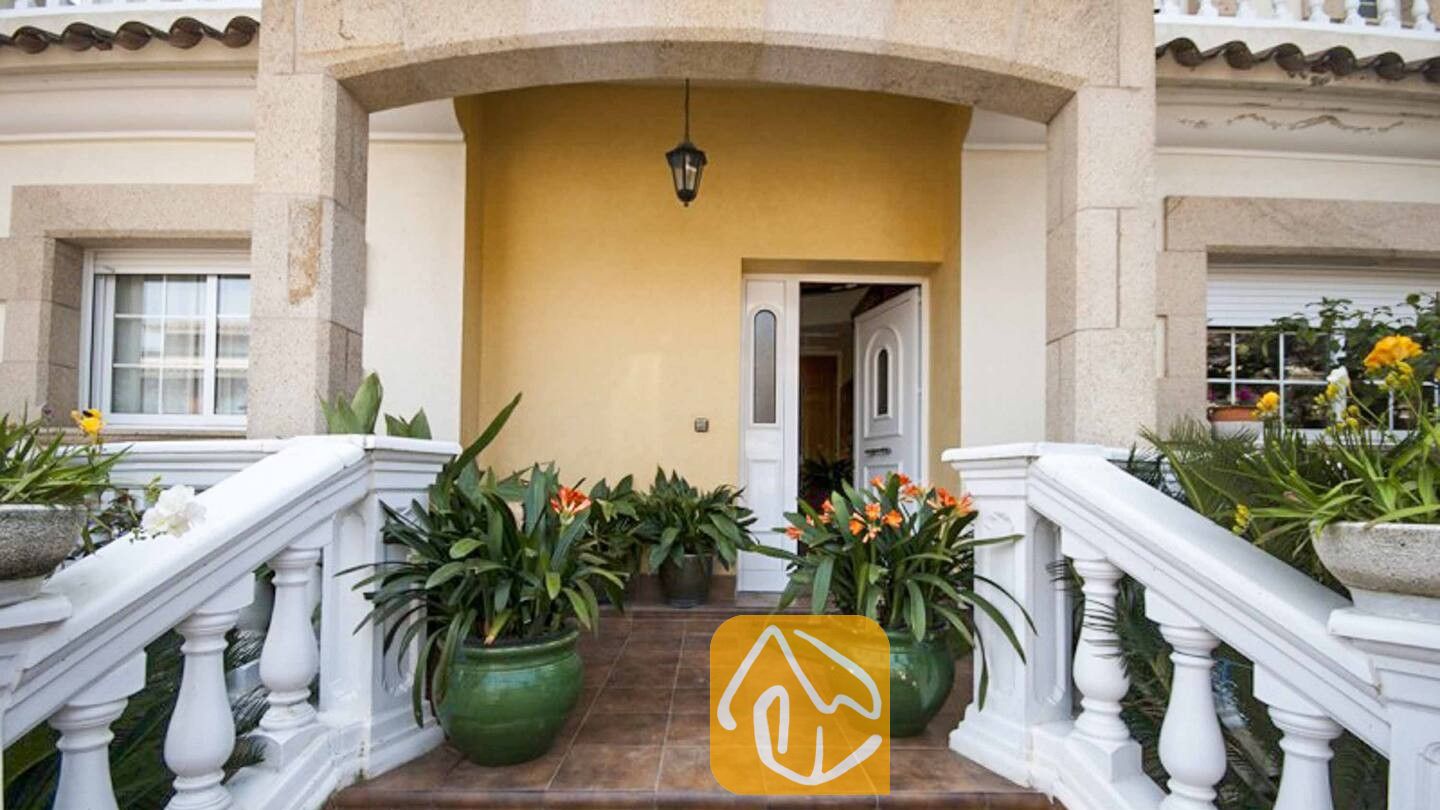 Vakantievilla's Costa Brava Spanje - Villa Mercedes Fenals - Entreeportaal van Villa Mercedes Fenals met stenen bogen, witte balustrades, betegelde treden en bloempotten met groene bladeren.