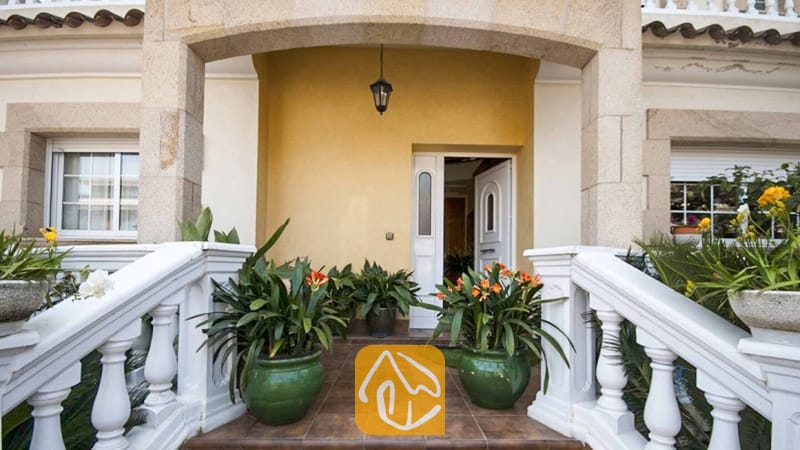 Ferienhäuser Costa Brava Spanien - Villa Mercedes Fenals - Eingangsbereich der Villa Mercedes Fenals mit steinernen Bögen, weißen Balustraden, gefliesten Stufen und Topfpflanzen mit grünem Blattwerk.