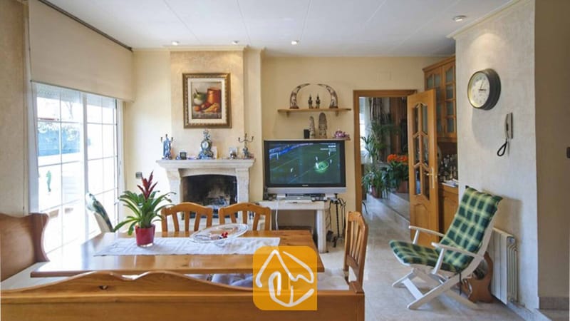 Ferienhäuser Costa Brava Spanien - Villa Mercedes Fenals - Wohn- und Essbereich mit Holzesstisch, Steinkamin und Fernseher in der Villa Mercedes Fenals.