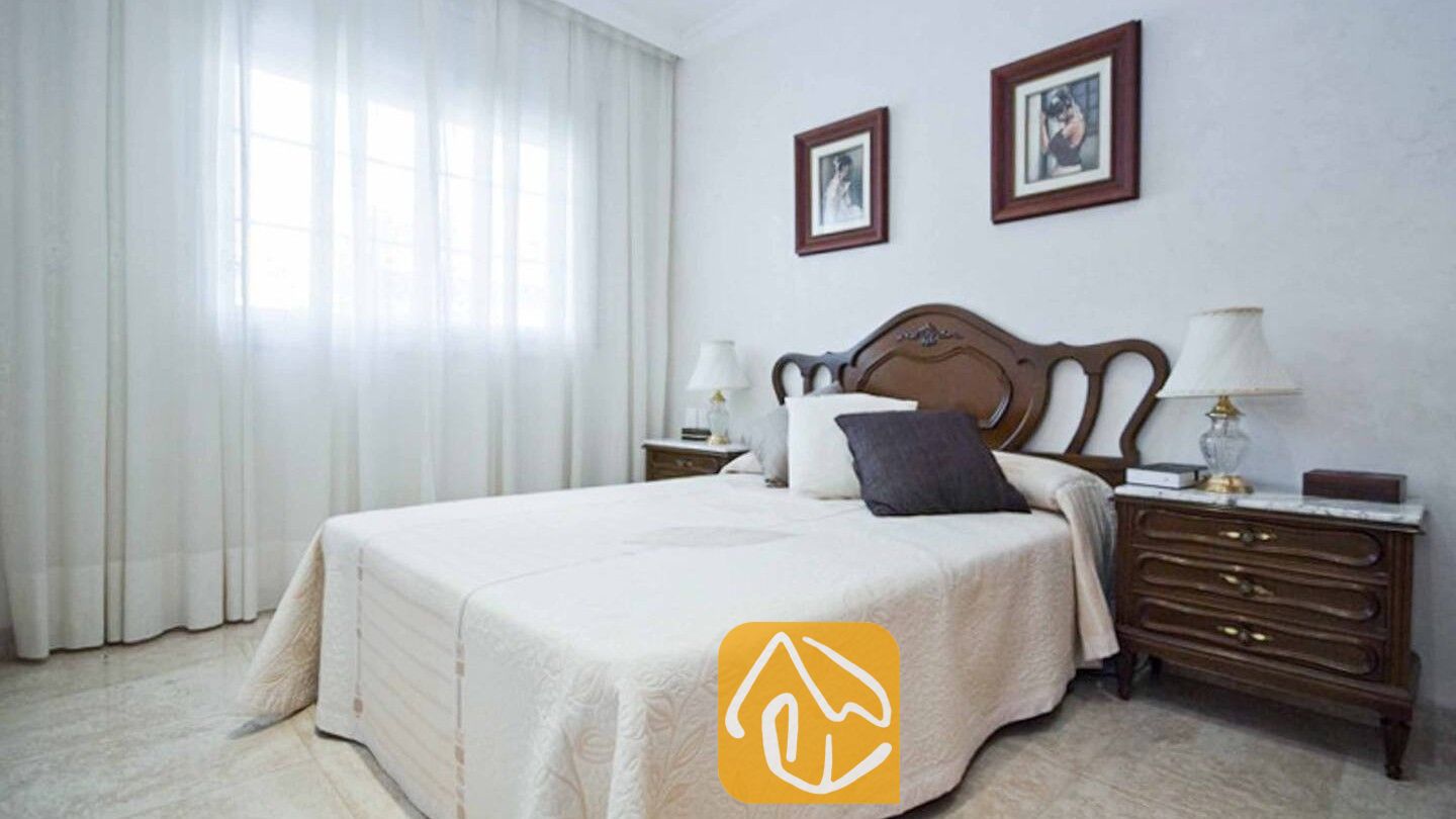 Vakantievilla's Costa Brava Spanje - Villa Mercedes Fenals - Slaapkamer met een donkerhouten hoofdbord, bijpassende nachtkastjes en licht beddengoed met patroon in Villa Mercedes Fenals