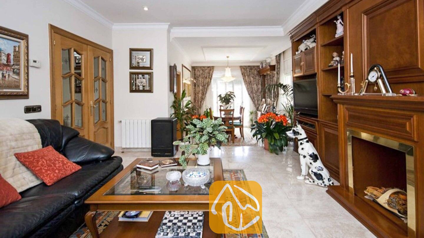 Vakantievilla's Costa Brava Spanje - Villa Mercedes Fenals - Woonkamer met een zwart leren bankstel, een houten salontafel en ingebouwde muurvullende planken rondom een open haard in Villa Mercedes Fenals.