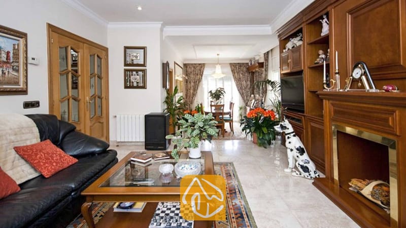 Ferienhäuser Costa Brava Spanien - Villa Mercedes Fenals - Wohnzimmer mit schwarzem Ledersofa, einem Couchtisch aus Holz und maßgefertigten Wandregalen rund um einen Kamin in der Villa Mercedes Fenals.