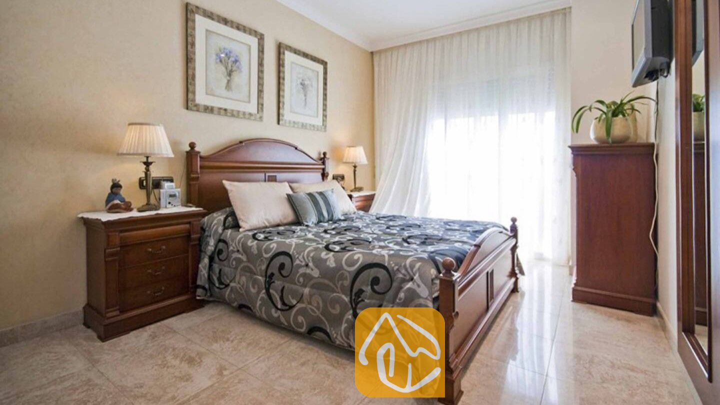 Vakantievilla's Costa Brava Spanje - Villa Mercedes Fenals - Slaapkamer met een donkerhouten bedframe, een patroonloos grijs dekbed (of: een grijs dekbed met patroon) en bijpassende nachtkastjes met lampen.